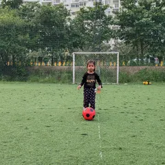 Taking her first steps in football. This young player stands confidently with her ball, ready to learn and play.