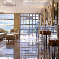 The lobby of a hotel project, where sunlight streams through large grid windows, reflecting off the polished marble floor. The design balances industrial touches with soft, comfortable furniture.