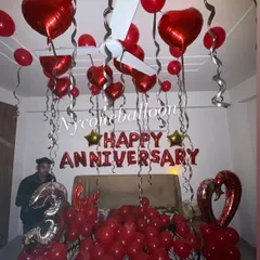 This is my classic anniversary room decoration service. The setup includes red 'HAPPY ANNIVERSARY' foil letters, dozens of red balloons covering the bed and ceiling, and a large number balloon to mark the special year, like this third anniversary celebration.