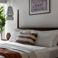 This master bedroom is designed as a calm, relaxing retreat. The modern-Indian aesthetic is centered around a classic wooden poster bed, complemented by a unique pendant light and a framed art piece that adds a touch of nostalgia.