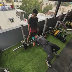 A wide-angle view of a client performing a bench press under my supervision, showcasing the safe and supportive training environment.