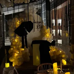 A moody, candlelit view of Naziya's bow-themed 30th birthday party. The combination of warm lights, white balloons, and black ribbon streamers created a sophisticated and intimate atmosphere.