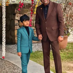 Style runs in the family. We had the pleasure of creating custom suits for Mr. Ritzbora and his son, coordinating a classic brown suit with a bold teal one for a festive occasion.