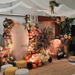 A beautiful boho-themed setup for a 30th birthday. The decor features a mix of textures with a macrame wall hanging, pampas grass, and a variety of seating options like poufs and stools, creating a relaxed yet stylish vibe.