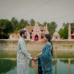 A stunning wide shot of a couple in traditional attire, holding hands before a beautiful temple and its reflection pond. This pre-wedding photo perfectly blends culture, love, and serene landscapes.