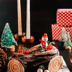 A classic Chocolate Yule Log (Bûche de Noël), decorated to look like a log from a winter forest. Complete with a tiny snowman and meringue mushrooms, it's a traditional centerpiece for your Christmas table.