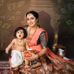 A look of surprise from little Krishna as he sits on his mother's lap, holding a pot of butter. The expressions are what make these themed shoots so memorable.
