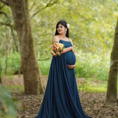 Standing amidst the trees, this portrait captures a feeling of peace and connection with nature. The flowing blue gown complements the greens of the forest perfectly.