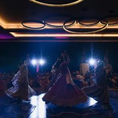 A dramatic shot of the bride and her bridesmaids during their sangeet performance. The backlighting and coordinated outfits create a powerful and visually stunning image.