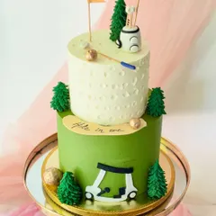 A "hole in one" celebration cake for a golf enthusiast. This two-tiered design features a dimpled top tier, a golf cart, and other course details made from fondant.