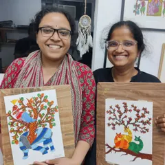 Two happy students from our Gond painting workshop pose with their unique creations, each telling a story through traditional motifs.