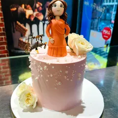 A full view of the personalized figurine cake. The combination of a custom topper and a classic cake design creates a truly special and memorable birthday centerpiece.