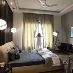 This warm and cozy bedroom is designed to welcome the morning sun, with large windows and light curtains. The room features a dark wood fluted panel wall behind the bed, which contrasts beautifully with the soft, neutral tones of the furnishings.