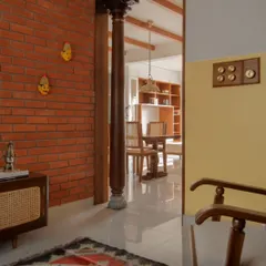 A view from the foyer into the dining area, framed by an antique wooden column. This transition space uses color blocking and material changes, from brick to plaster, to define zones within the open layout.