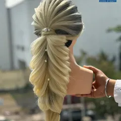 A demonstration of a stunning pull-through braid on a blonde mannequin. The style is accented with pearls, showcasing how to create voluminous and visually complex braids.
