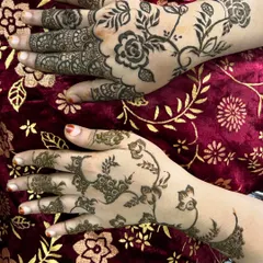 This image shows two different styles side-by-side. One hand has a dense, traditional pattern while the other features a more modern, spaced-out floral vine, showing the versatility of my henna.