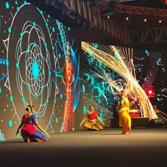 A dynamic scene from the 'Fusion of Epochs' performance at the AWS AI Conclave. The dancers interact with real-time generative AI visuals, creating a seamless blend of human movement and machine-generated art.