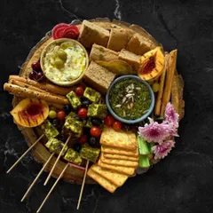 Take your party to Italy with this flavorful platter. It features my pesto grilled tofu skewers, soft focaccia bread, crunchy bread sticks, and crackers. To go with it, I include a fresh pesto dip and a savory olive and feta dip, making it a complete Italian appetizer experience.