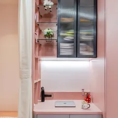 Designed for a chic pastel room, this compact desk is perfect for smaller spaces. It features integrated drawers, power access, and is connected to a vertical shelving unit with both open and closed storage for a tidy look.