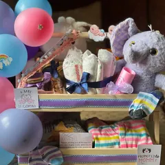 A closer look at the newborn hamper, focusing on the plush elephant and neatly rolled diapers tied with a ribbon. It’s a gift that is both adorable and practical.