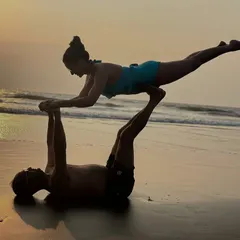 Partner yoga is about finding balance together. This acro-yoga pose, often called "Flying Whale" or "Bird," requires trust, strength, and a bit of playfulness. It’s a beautiful way to connect and support each other, set against the calming backdrop of the ocean.