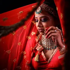 A close-up shot of the bride holding her nath. The intricate details of the eye makeup and the 'bindi' are highlighted here.