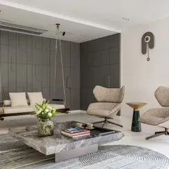The formal living area at Park West is a study in serene elegance. I paired a minimalist indoor swing with sculptural armchairs and a monolithic stone coffee table to create a space that feels both sophisticated and welcoming. The paneled grey wall conceals storage, maintaining a clean and uncluttered aesthetic.