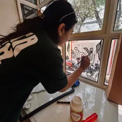 Sometimes the canvas isn't a wall, but glass. Here I am, lost in the process of painting custom illustrations directly onto the window panels of a cafe.