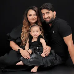 A classic family portrait. Posed against a simple black background, the focus is entirely on the love and connection between this beautiful family of three.