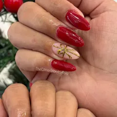A classic Christmas look with glossy red nails and a single accent nail featuring a delicate, hand-painted gold bow.