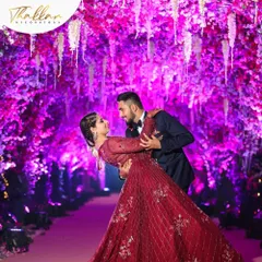 A romantic couple's portrait captured within a breathtaking floral tunnel. The vibrant purple lighting enhances the dense canopy of flowers, creating a magical and intimate setting perfect for a reception.