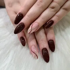 A sophisticated and warm set with deep brown nails and sheer accent nails featuring delicate, intersecting glitter lines.