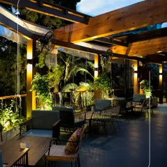 The outdoor seating area at Botanica provides a chic and comfortable space for an evening dinner or drinks, with warm lighting and a view of the gardens.