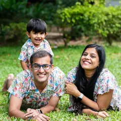 A relaxed family portrait with parents and their son lying on the grass, all wearing matching floral shirts.
