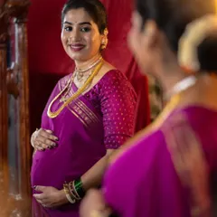 A lovely reflection shot capturing the joy of pregnancy. Her makeup is soft and natural, with a focus on glowing skin that enhances her happiness.