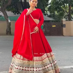 A full-length shot showcasing the complete silhouette of the red velvet bridal lehenga. The long sleeves and coordinated dupatta create a cohesive and elegant look, ideal for a traditional North Indian or fusion wedding ceremony.