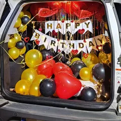 Another car trunk surprise, this one using red, black, and yellow balloons. The decoration is lit with fairy lights and includes a 'Happy Birthday' banner for a festive reveal.