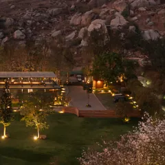This wide evening shot shows the entire project settled into the rocky hillside. Our landscape lighting strategy focuses on accentuating the natural topography and pathways, creating a harmonious and functional nighttime environment.