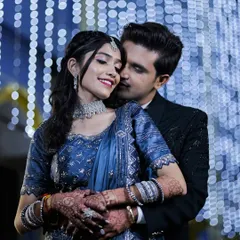 A classic romantic pose against a backdrop of blue fairy lights, highlighting the couple's elegant blue outfits.