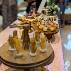 A sophisticated setup for a luxury brand event, showcasing tiered displays of mini burgers and elegant truffle cigar rolls. I ensure the presentation always matches the caliber of the occasion.