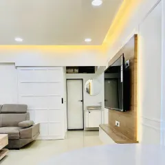 This image showcases a clean and modern living room design. Notice the custom sliding door that saves space, the sleek floating TV unit with backlighting, and the seamless connection to the entryway, creating a harmonious and uncluttered feel.