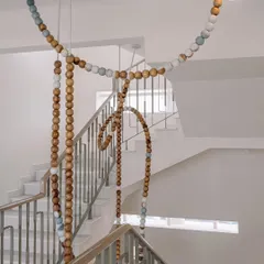 A view of the LUNA installation from the top of the staircase. The loops and drapes of the beads create a playful, sculptural form against the clean white walls of the penthouse.