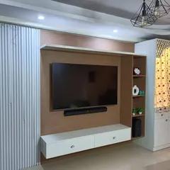 This comprehensive living room unit combines a TV console with a beautiful pooja mandir, featuring white fluted panels and light wood tones for a cohesive look.