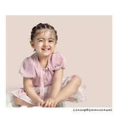 A bright and cheerful portrait of a young girl with a heart-melting, scrunch-nosed smile, showcasing the pure, unfiltered joy of childhood in a simple studio setting.