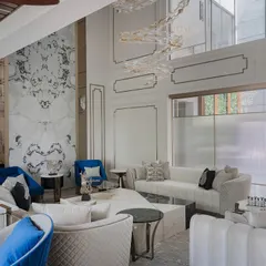 Another angle of the poolside living room, this shot shows the interplay of textures, from the quilted sofas to the smooth marble feature wall. The layout is intentionally open to create a sense of flow and visual connectivity across the different zones.