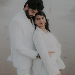 A stylish portrait of a couple on a Goa beach, dressed in all white. The soft evening light and the ocean backdrop create a serene and romantic atmosphere for this destination pre-wedding shoot.