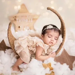 Another pose from our popular starry night theme. Here, she's dressed in a beautiful lace romper, sleeping on her side on the crescent moon prop.