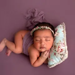 Another angle of this peaceful pose. The soft lighting and simple wrap highlight the baby's delicate features and tiny curled-up body.
