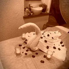 Every detail in our treatment rooms is arranged to create a peaceful atmosphere. Here, a massage bed is prepared with a towel swan and soft candlelight, setting the stage for your journey into relaxation.