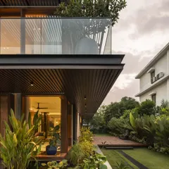 As evening falls, the warm interior lighting of Villa re:FORM highlights the clean lines of the architecture. The cantilevered balcony and lower-level glazing connect the home to its tropical landscape and bio-pond.